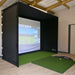 Indoor golf simulator setup with screen and mat on a wooden floor